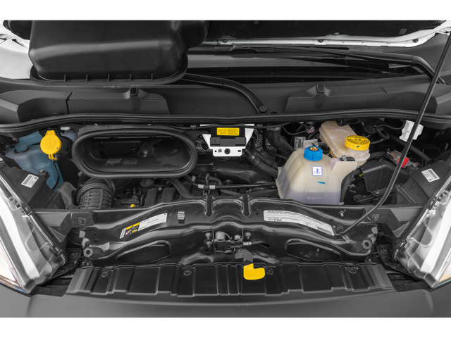 Engine bay of a cargo van with visible components including coolant reservoir