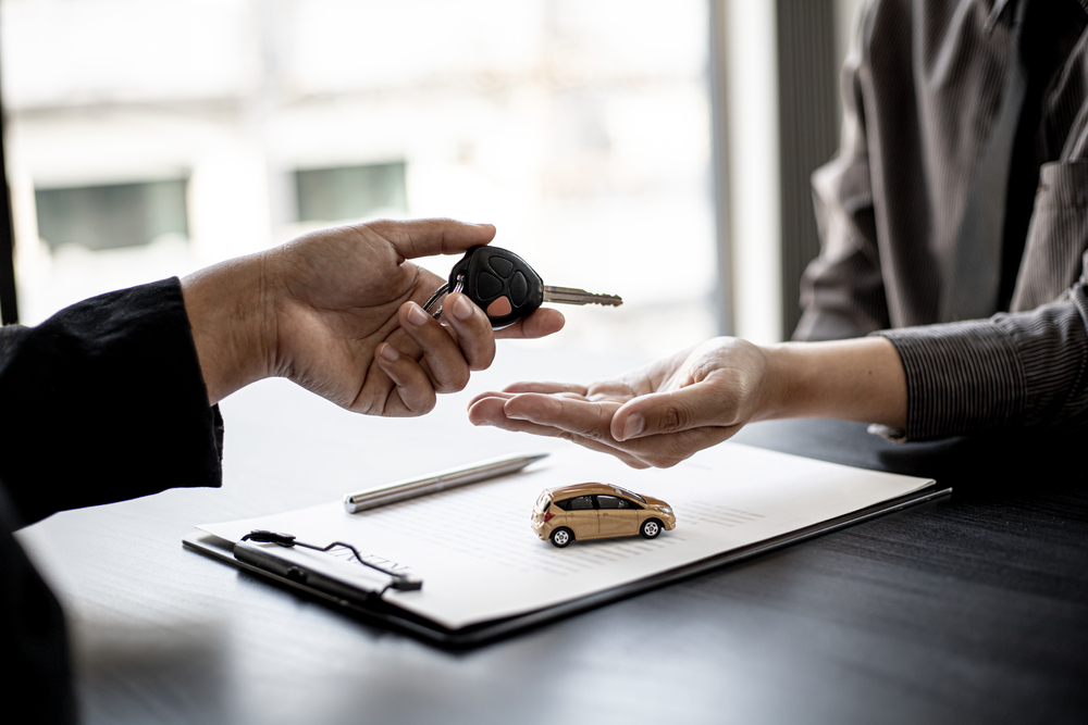 A man hands a car key to a woman, symbolizing a successful car financing transaction at a Chrysler dealership.