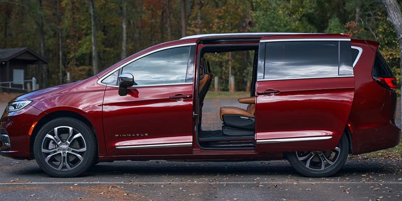 Side view of a red minivan with sliding door open, revealing second-row seating