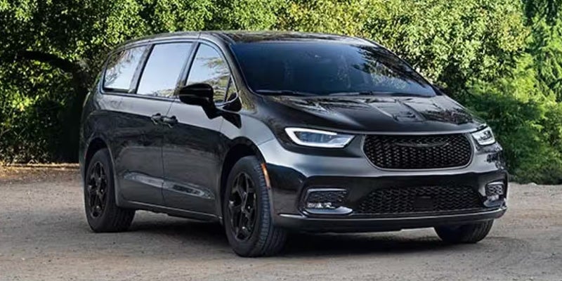 Black minivan parked outdoors on a dirt surface
