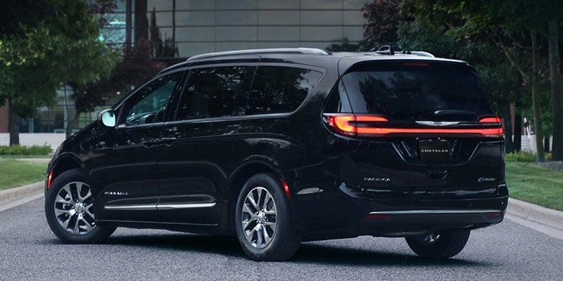 Black minivan driving on a road, shown from rear three-quarter angle with LED taillights