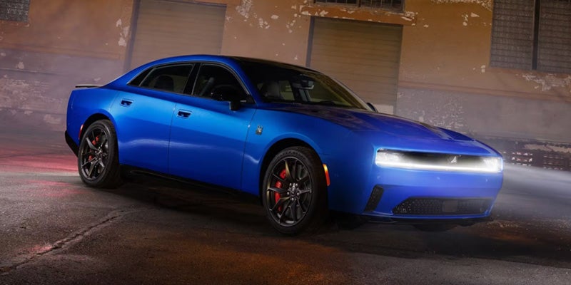 Blue sports sedan parked outdoors at night with LED headlights on, black wheels