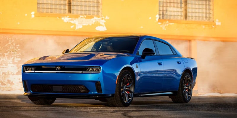 Blue sports sedan shown in front three-quarter view parked near a building