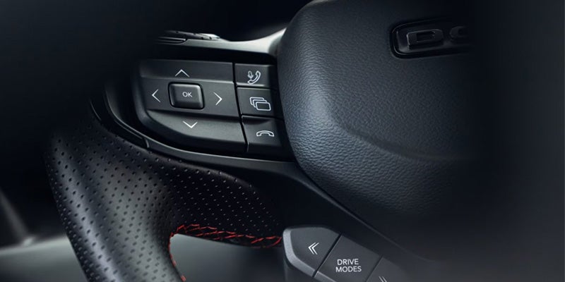 Close-up of steering wheel controls including buttons for navigation