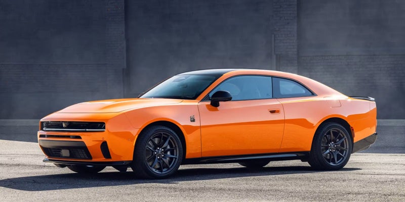 Close-up of the front of an orange performance sedan highlighting grille, air intake, and lower bumper design.