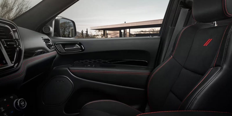 Front passenger seat area with black upholstery, red stitching