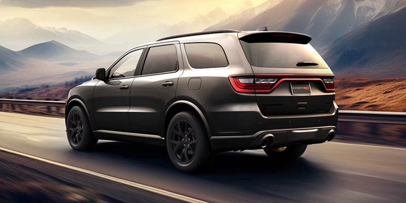 Gray SUV driving on a scenic road with mountains in the background