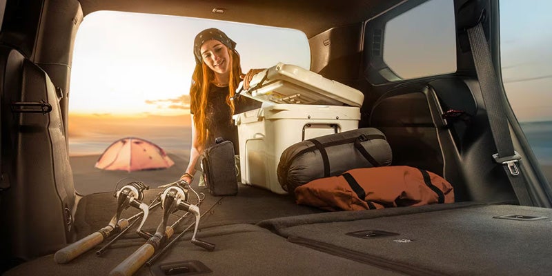 Rear cargo area of an SUV with folded seats holding camping gear