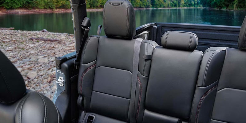 Rear seating area of a pickup truck with black leather seats, headrests, center armrest
