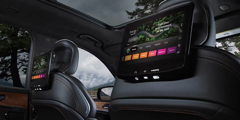Rear seat entertainment system with dual screens mounted behind headrests displaying apps