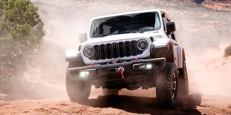 The SUV is driving through a dusty dirt trail or desert-like environment