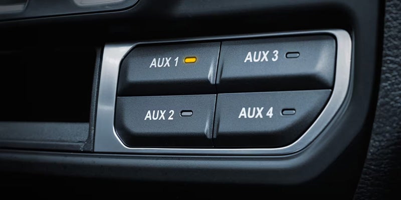 Close-up of auxiliary switch controls labeled AUX 1 through AUX 4 inside a Jeep Wrangler