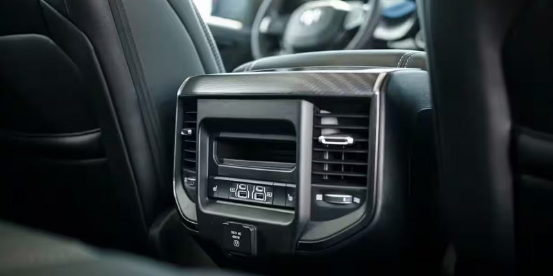 Rear seat view showing back console air vents, charging ports, and control buttons inside a RAM truck interior