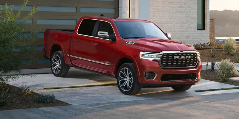Red RAM pickup truck parked in a modern driveway in front of a house
