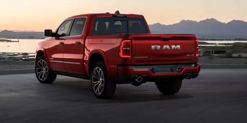 Rear view of a red RAM pickup truck driving on a road at sunset