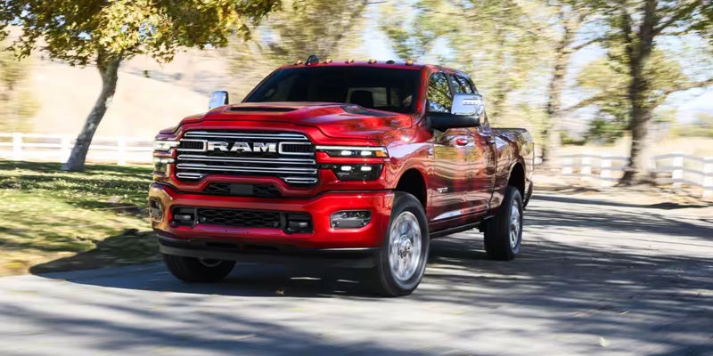 Red RAM heavy-duty pickup truck driving on a tree-lined road