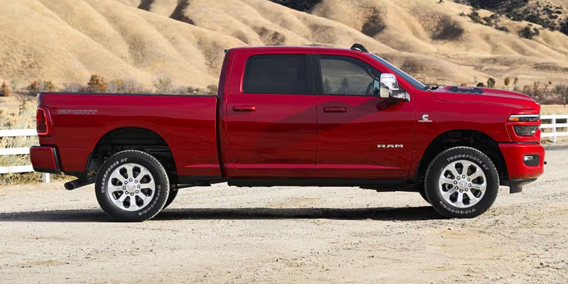 Side view of a red RAM pickup truck parked in a dry, hilly landscape
