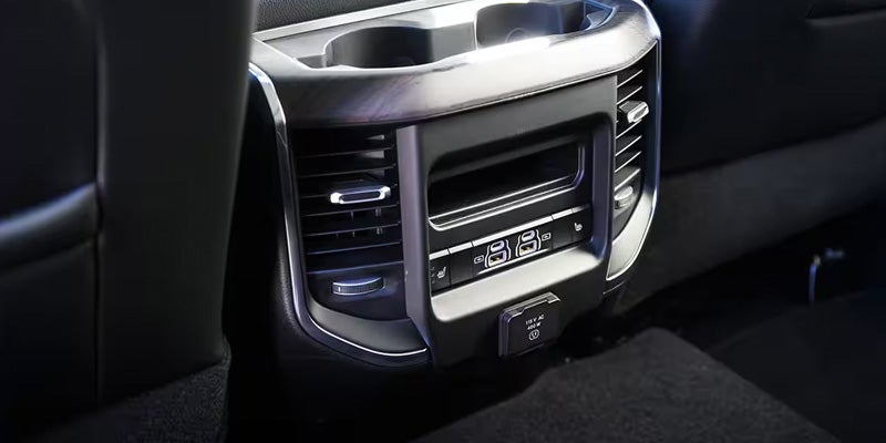 Rear seat console inside a vehicle showing air vents, climate controls
