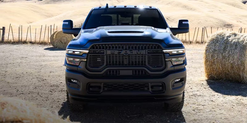 Front view of a dark-colored RAM truck parked on dirt ground