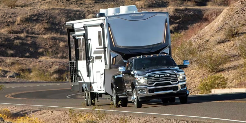 Black RAM heavy-duty pickup truck towing a large RV trailer